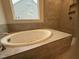 Large soaking tub surrounded by tile with a view to the outside at 145 Green Haven Blvd # 83, Youngsville, NC 27596