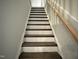 Carpeted staircase leads to upper floors with stained handrail and white risers at 145 Green Haven Blvd # 83, Youngsville, NC 27596