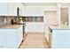 Bright kitchen with white cabinetry, stainless steel appliances, a gray backsplash, and center island with sink at 727 Putney Hill Rd, Zebulon, NC 27597