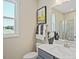 Bright bathroom featuring a gray vanity, quartz countertop, framed mirror, and tiled shower with glass doors at 512 Lemon Daisy Ln, Knightdale, NC 27545
