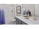 Bathroom with double vanity, granite countertops, modern faucets, and tub-shower combination with blue curtain at 512 Lemon Daisy Ln, Knightdale, NC 27545
