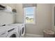 Well-lit laundry room equipped with modern washer and dryer, overhead shelf, and a window for natural light at 512 Lemon Daisy Ln, Knightdale, NC 27545