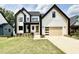 Modern farmhouse with black trim, white siding, wood garage door, and green lawn at 205 Red Cardinal Ct, Youngsville, NC 27596