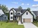 New construction home with modern farmhouse design, detailed trim, manicured lawn and wood garage door at 205 Red Cardinal Ct, Youngsville, NC 27596