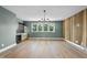 Open living room with decorative wood wall, hardwood floors, wet bar, and bright windows at 205 Red Cardinal Ct, Youngsville, NC 27596
