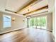 Open living space features hardwood floors, wooden beam ceiling and glass sliding doors to a deck at 205 Red Cardinal Ct, Youngsville, NC 27596