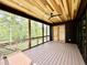 Covered porch with wood floors, ceiling, and railings overlooking wooded backyard at 205 Red Cardinal Ct, Youngsville, NC 27596
