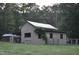 Rustic barn featuring a covered shelter, an open enclosure, and mature landscaping in the surrounding property at 7610 Buckhorn Rd, Hillsborough, NC 27278