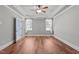 Gray bedroom with wood floors, ceiling fan and two windows with sheer curtains at 6720 Fawn Hoof Trl, Holly Springs, NC 27540