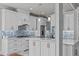Open kitchen with white cabinets, center island, and a blue glass tile backsplash at 6720 Fawn Hoof Trl, Holly Springs, NC 27540