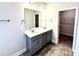 Bathroom features a double vanity with gray cabinets and granite countertop with a view to the walk-in closet at 55 Capeside Ct, Lillington, NC 27546
