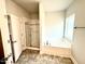 Bright bathroom with a glass-enclosed shower, white soaker tub, and window overlooking backyard at 55 Capeside Ct, Lillington, NC 27546