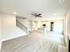 Open-concept living room with gray wood floors, fireplace, staircase, and a view into the kitchen at 31 Capeside Ct, Lillington, NC 27546