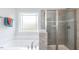 Bathroom showcasing a soaking tub with a large window and glass enclosed shower with gray tile at 19 Streamline Ct, Lillington, NC 27546