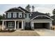 Charming two-story home with gray siding, stone accents, inviting covered porch, and an attached two-car garage at 19 Streamline Ct, Lillington, NC 27546