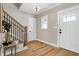 Charming entryway with hardwood floors, staircase with iron spindles, and transom window above the front door at 417 E Moore St, Apex, NC 27502