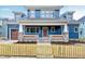 Charming blue two-story home boasts stone accents, a welcoming front porch, and a quaint yellow picket fence at 417 E Moore St, Apex, NC 27502