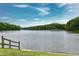 Scenic view of a serene lake surrounded by lush trees with a weathered wooden fence at 417 E Moore St, Apex, NC 27502