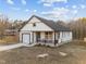 Picture of the house with an attached garage, a front porch with metal chairs, and a well-maintained yard at 1101 Ridge Rd, Roxboro, NC 27573