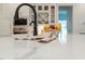 Kitchen island featuring a black gooseneck faucet, white countertops, and decorative fruit bowl at 60 Citori Ct, Pittsboro, NC 27312