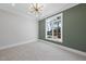 Empty bedroom featuring neutral carpet, a modern light fixture, and a large window at 701 Dartmouth Rd, Raleigh, NC 27609