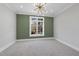 Empty bedroom featuring neutral carpet, a modern light fixture, and a large window at 701 Dartmouth Rd, Raleigh, NC 27609
