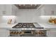 Professional-grade gas range with a stainless steel hood, sleek white cabinetry, and a white quartz backsplash at 701 Dartmouth Rd, Raleigh, NC 27609