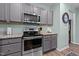 Modern kitchen with gray cabinets, stainless steel appliances, and granite countertops at 108 Cullen Ct, Clayton, NC 27520