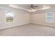 Spacious carpeted main bedroom with a tray ceiling and natural light from two windows at 347 Hopewell Branch Ct, Smithfield, NC 27577