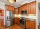 Updated kitchen with stainless steel appliances, warm wood cabinetry, and modern lighting fixtures at 102 Preston Pines Dr, Cary, NC 27513