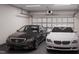 Spacious two-car garage with a black car and a white car parked inside under bright overhead lights at 1206 Holding Village Way, Wake Forest, NC 27587