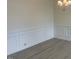 This dining room features elegant white wainscoting, light wood-look flooring, and a modern chandelier at 1528 Maelyn Way, Fuquay Varina, NC 27526