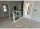 Upstairs hallway featuring a modern railing with horizontal slats, white walls, and white door frames at 2400 Adrift Rd, Fuquay Varina, NC 27526