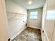 An empty laundry room features tile flooring, a wire shelf, and a window for natural light at 324 Bishop Ln, Sanford, NC 27330