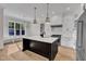 Open kitchen with white cabinets, black island, stainless steel appliances and hardwood flooring at 113 S Ennis St, Fuquay Varina, NC 27526