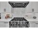 Close-up of a gas range with stainless steel vent hood and white subway tile backsplash at 113 S Ennis St, Fuquay Varina, NC 27526