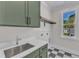 Well-lit laundry room features sage green cabinets, quartz countertop and a classic checkered floor at 113 S Ennis St, Fuquay Varina, NC 27526