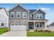 Beautiful two-story home featuring a stone facade, gray siding, a white garage door and a well-manicured lawn at 929 Kinglet House Rd, Knightdale, NC 27545