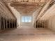 Insulated attic space with exposed beams and a window for natural light at 7000 North Ridge Dr, Raleigh, NC 27615
