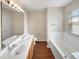 Elegant bathroom featuring double sinks, a large mirror, wood-look floors and a tiled tub at 330 Gilman Ln # 106, Raleigh, NC 27610