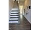 Bright hallway featuring hardwood floors, staircase with white risers and natural wood railing at 2038 Fishamble St, Fuquay Varina, NC 27526