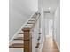 Hallway with wood floors and a staircase featuring a wood handrail and white risers, leading to an open doorway at 2038 Fishamble St, Fuquay Varina, NC 27526