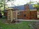 Backyard view showcasing a brick chimney, patio, and a decorative garden trellis at 301 Briarcliff Dr, Dunn, NC 28334