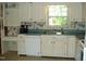 Traditional kitchen featuring white cabinetry, floral wallpaper, and stainless steel sink at 301 Briarcliff Dr, Dunn, NC 28334