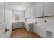 Bright laundry room with wooden floors, gray cabinets and countertops, and a window at 126 E Drewry Ln, Raleigh, NC 27609