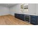 Wet bar with blue cabinets, wine fridge, marble countertops, and large window in living area at 126 E Drewry Ln, Raleigh, NC 27609