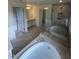An elegant bathroom features a large soaking tub, glass-enclosed shower, and bright vanity lighting at 23 Quail Pt Cir, Clayton, NC 27520