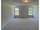 Spacious bedroom showcasing neutral carpet, two large windows, and a tray ceiling at 23 Quail Pt Cir, Clayton, NC 27520