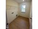 Well-lit laundry room features wood-look floors, shelving, and hookups for washer and dryer at 23 Quail Pt Cir, Clayton, NC 27520