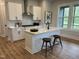 Well-lit kitchen with white cabinets, stainless steel appliances, a kitchen island, and stylish bar stools at 230 Grading Stick Ct, Angier, NC 27501